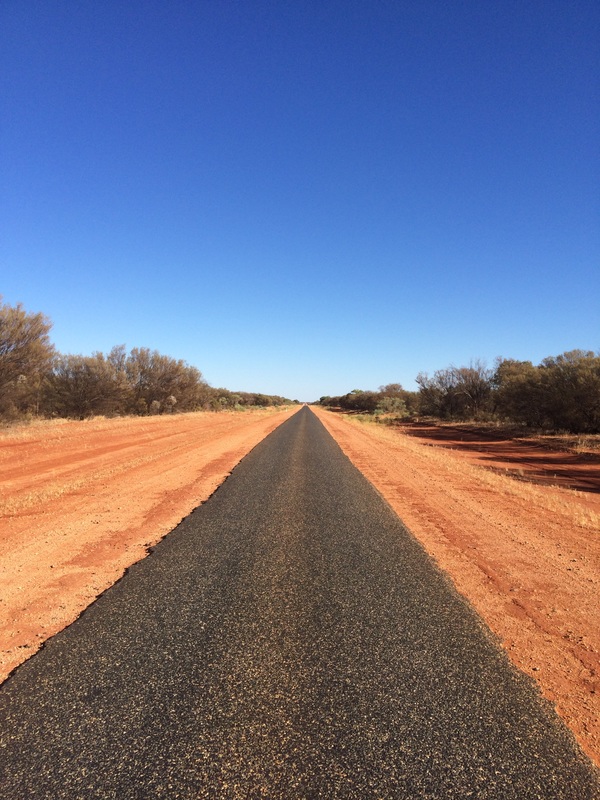 View down an isolated road with red dirt on both sides