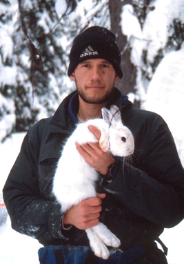 Aaron Wirsing holding a snowshoe hare outdoors in Idaho