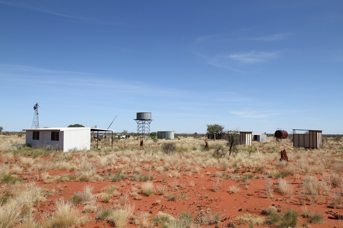 Small buildings in Australian outback with red dirt and small plants 