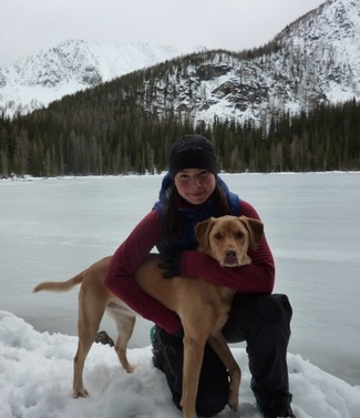Jessica Bolis with a dog in front of a frozen lake in the mountains