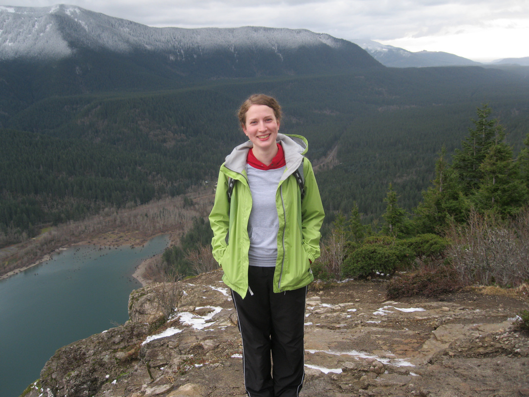 Kelsey Vitense standing on top of a mountain with a lake below