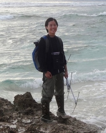 Linda Uyeda standing on rocks in an intertidal area, holding a telemetry antennae